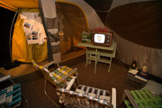 Camp Up To Now installation by Ayin Es, interior tent with tv, car battery, ants, snake and Torah at Shulamit Gallery, Venice, CA