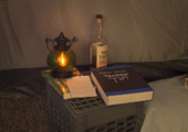 Camp Up To Now installation by Ayin Es, interior tent showing Torah and lantern on milk crate table, with notes